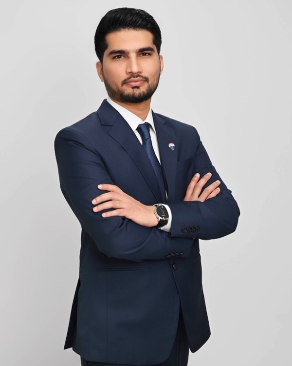 Sharry Minhas, RE/MAX Bozz Realty, in a navy suit with a RE/MAX lapel pin